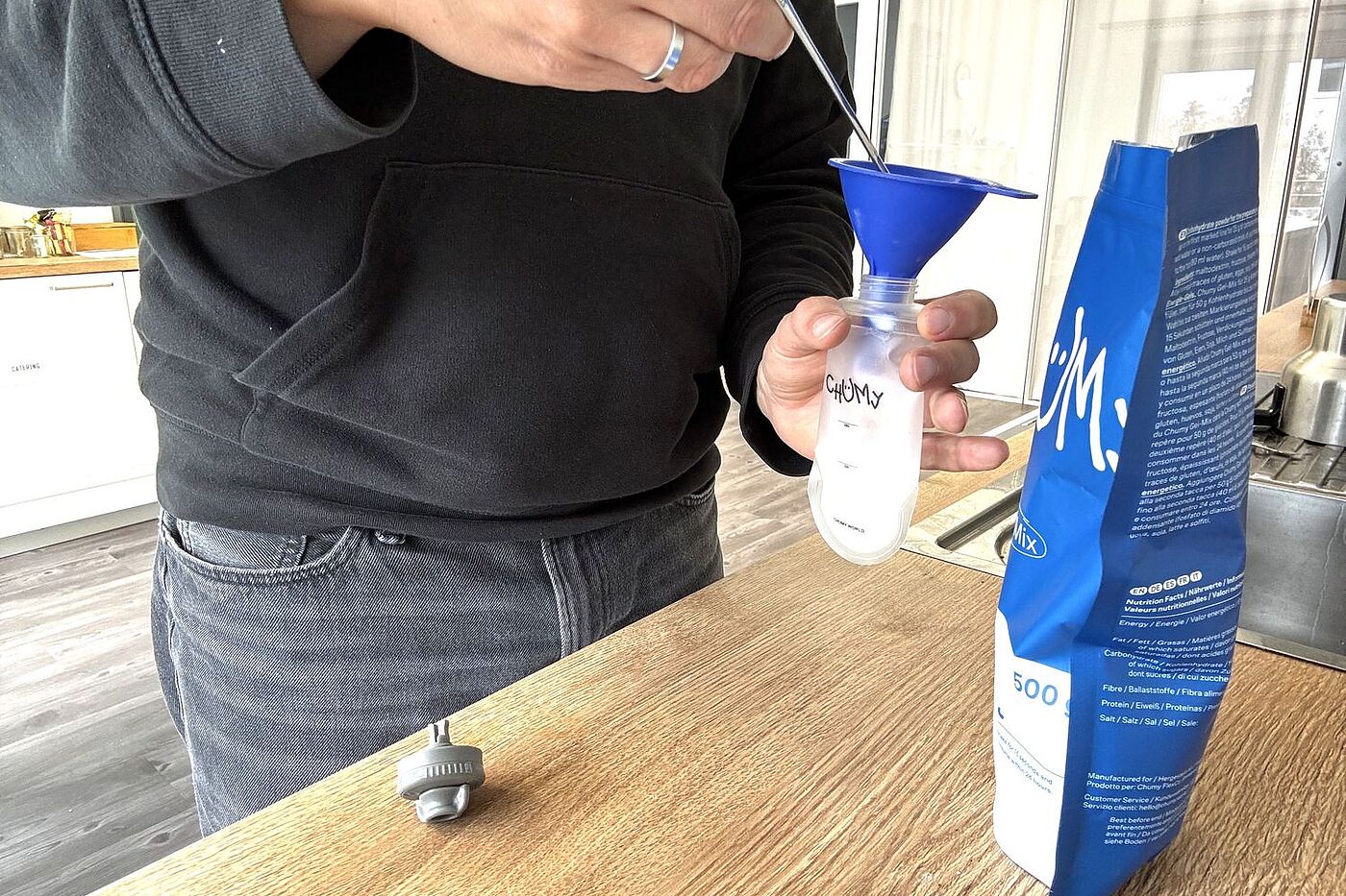 Gel mixen Eine Person steht an einer Küchenzeile und füllt Gelpulver mit einem Trichter in ein Fläschchen.